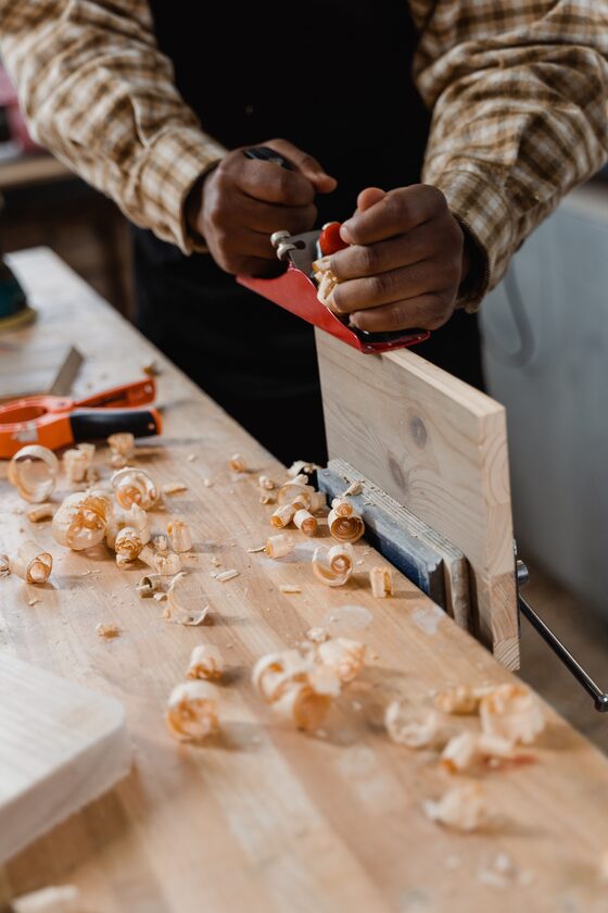 Woodworker hand-planing a board held to the workbench by a clamp