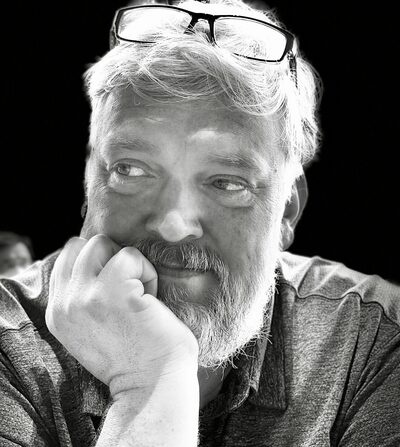 Black-and-white portrait of Joel Helbling, resting his chin on his hand
