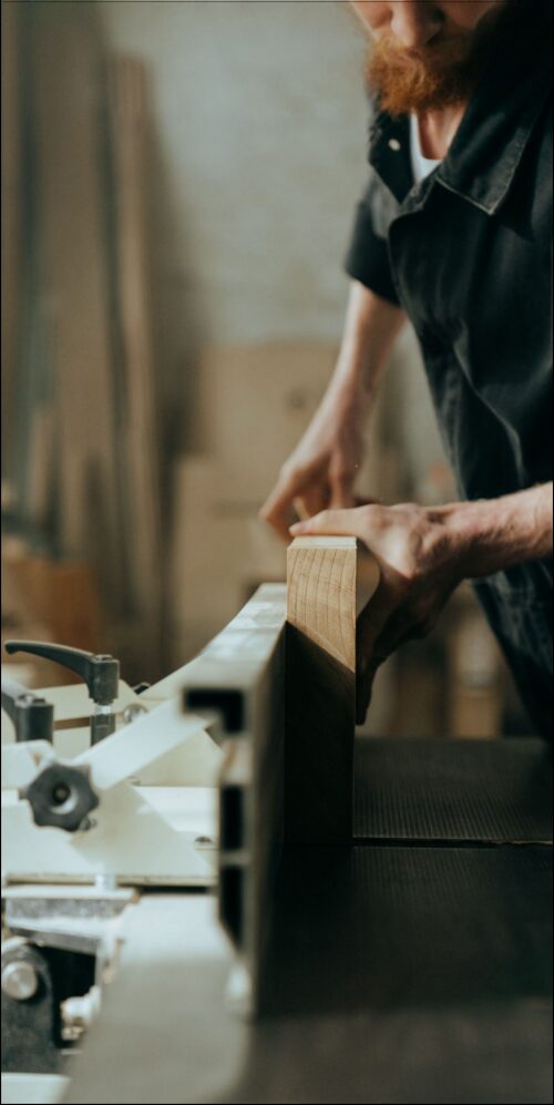 Woodworker pushing a board across a jointer to flatten its face