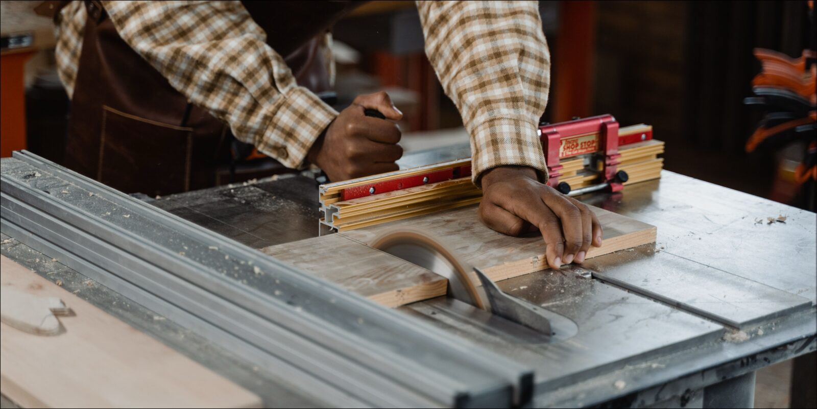 Woodworker ripping a board on a table saw, the workpiece held against the fence